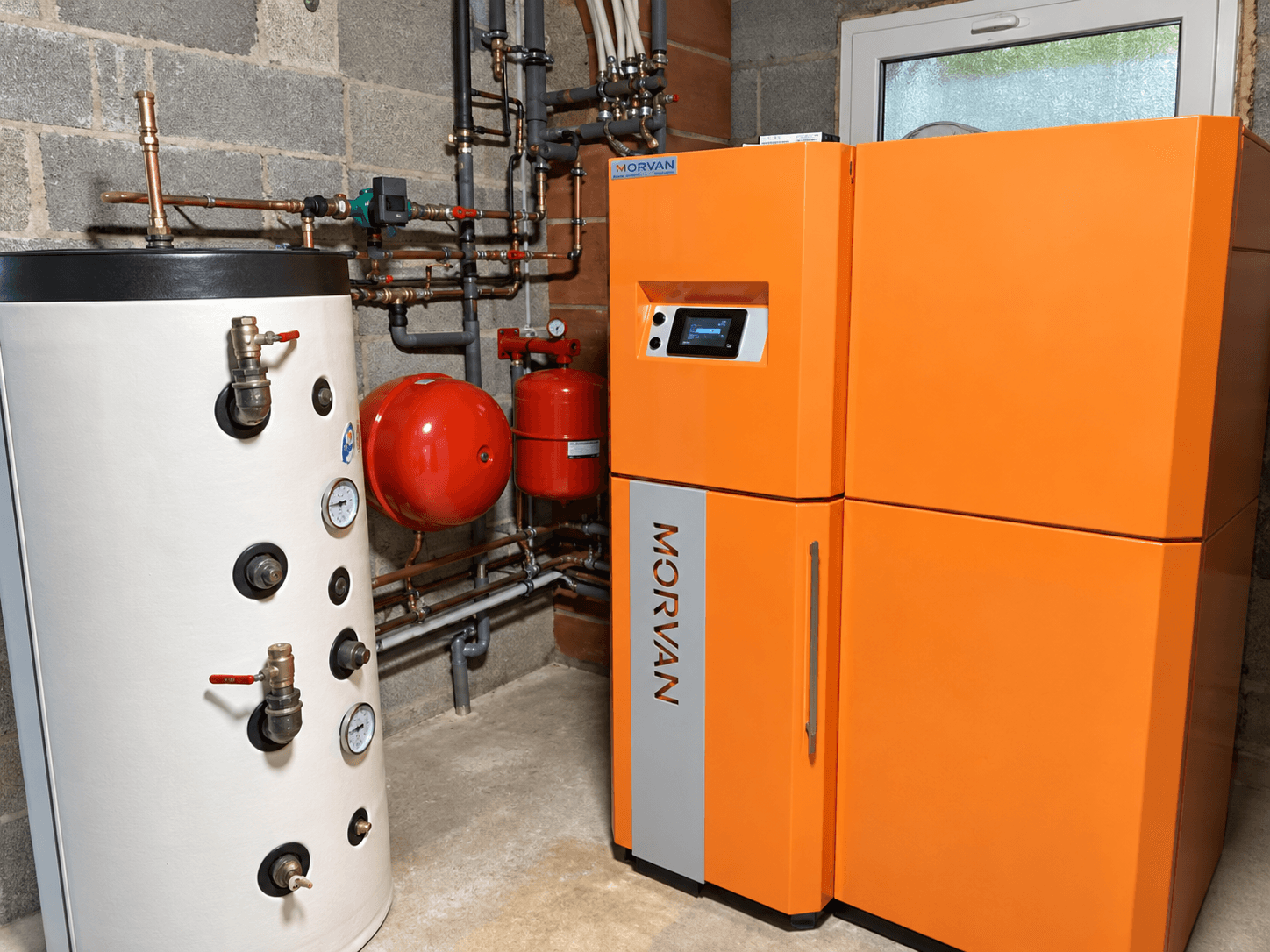 Installation de chauffage avec chaudière orange et ballon blanc